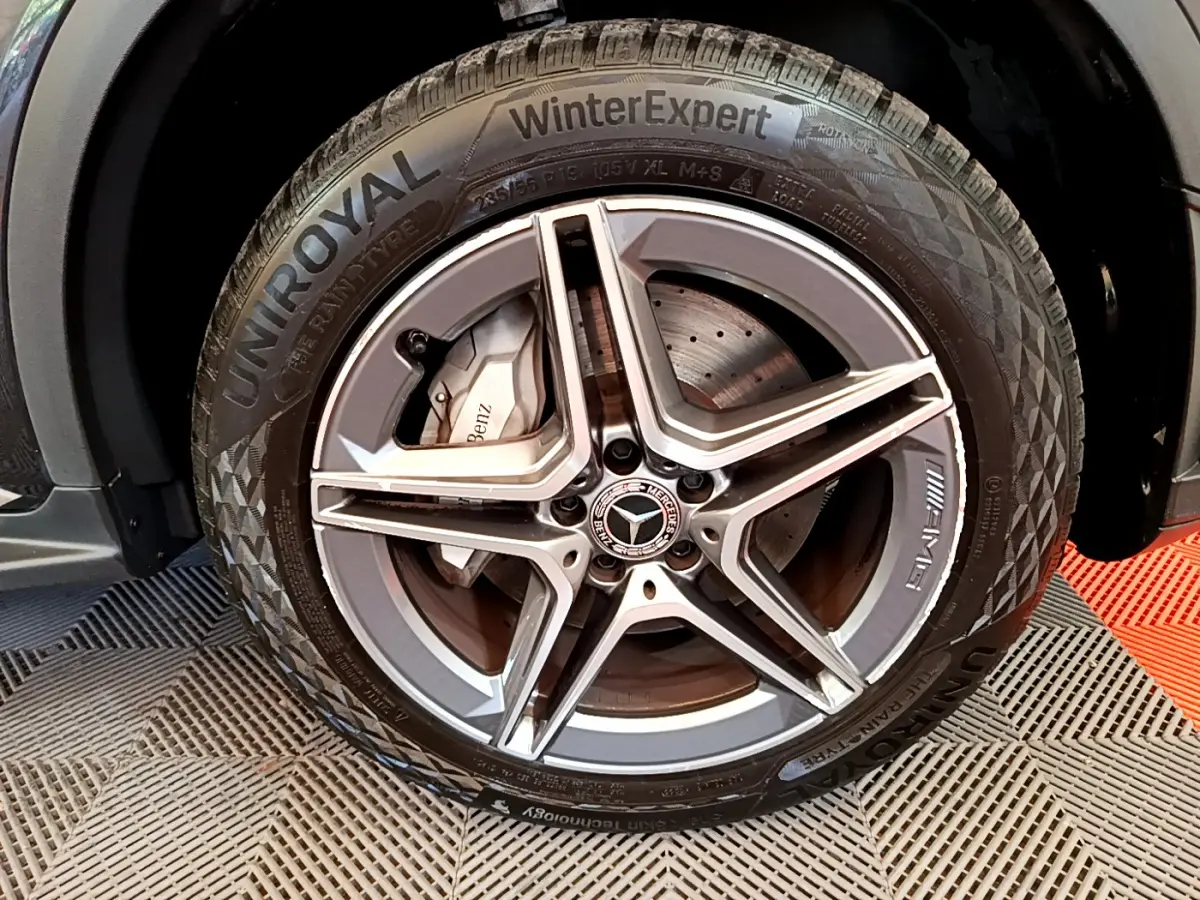 Gros plan sur la roue avant droite du Mercedes GLC 300 E AMG Line gris foncé avec jante AMG et pneu Uniroyal WinterExpert.