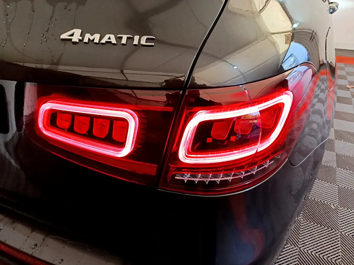 Gros plan sur le feu arrière droit rouge et le logo 4MATIC d’un Mercedes GLC 300 E AMG Line gris foncé.