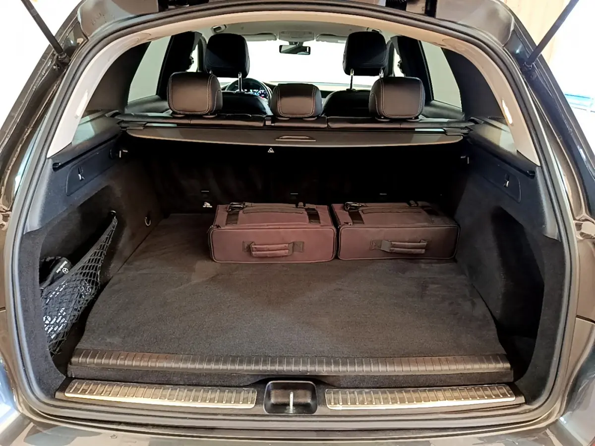 Coffre ouvert d'un Mercedes GLC 300 E AMG Line gris foncé, avec deux valises noires posées à l'intérieur.