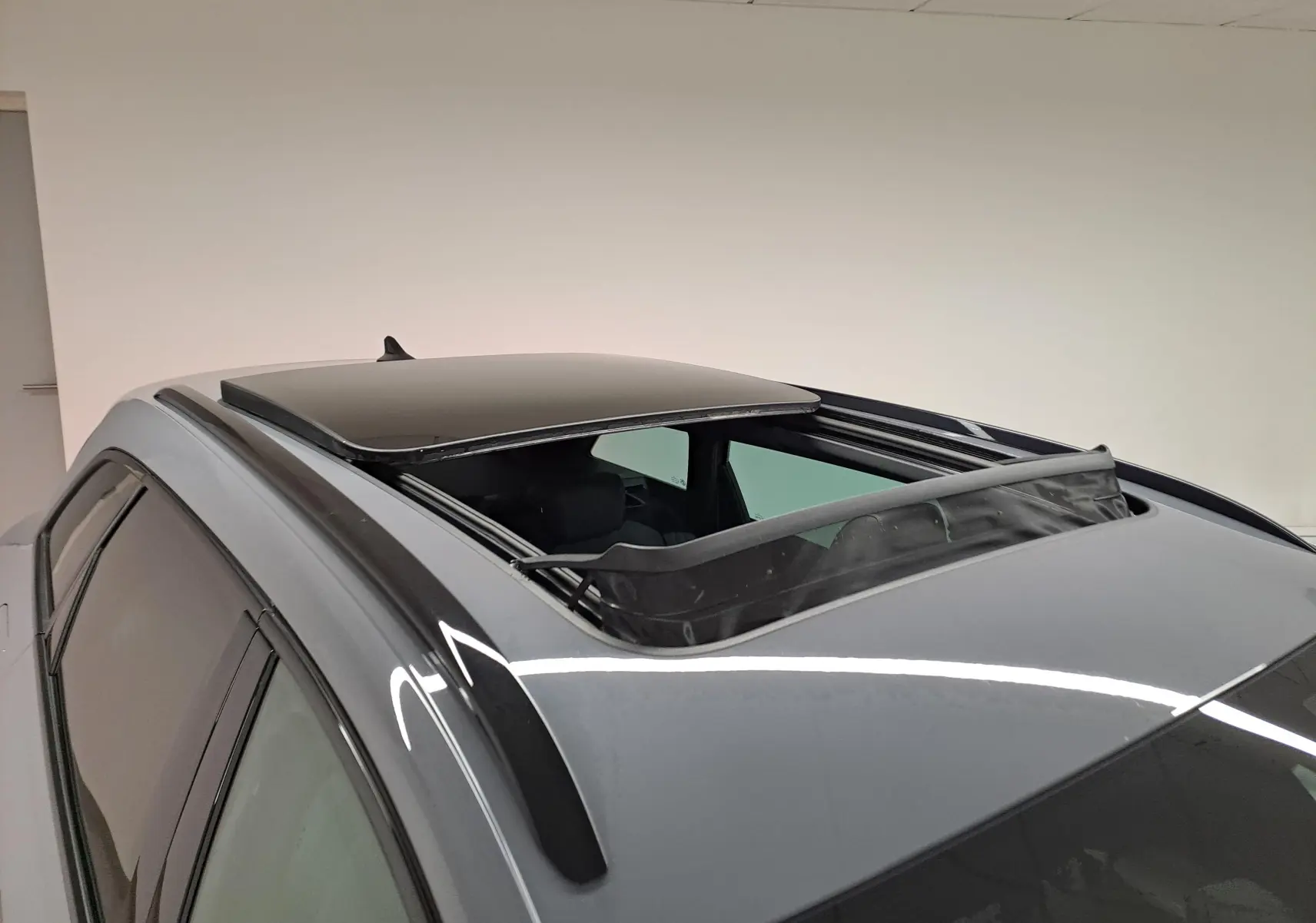 Vue en plongée du toit ouvrant panoramique ouvert sur la CUPRA LEON ST gris Graphène, avec barres de toit noires visibles.