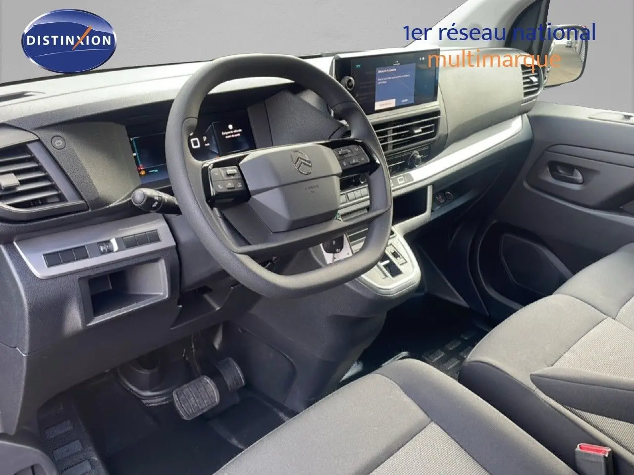 Vue intérieure côté conducteur du Citroën Jumpy gris titane, montrant le volant, tableau de bord et console centrale moderne.