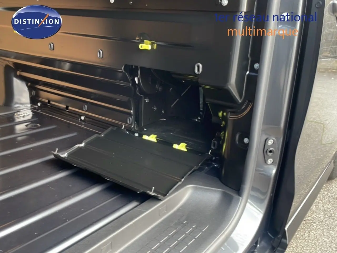 Vue intérieure du compartiment de chargement du Citroën Jumpy gris titane, avec porte latérale ouverte montrant le plancher et un espace de rangement.