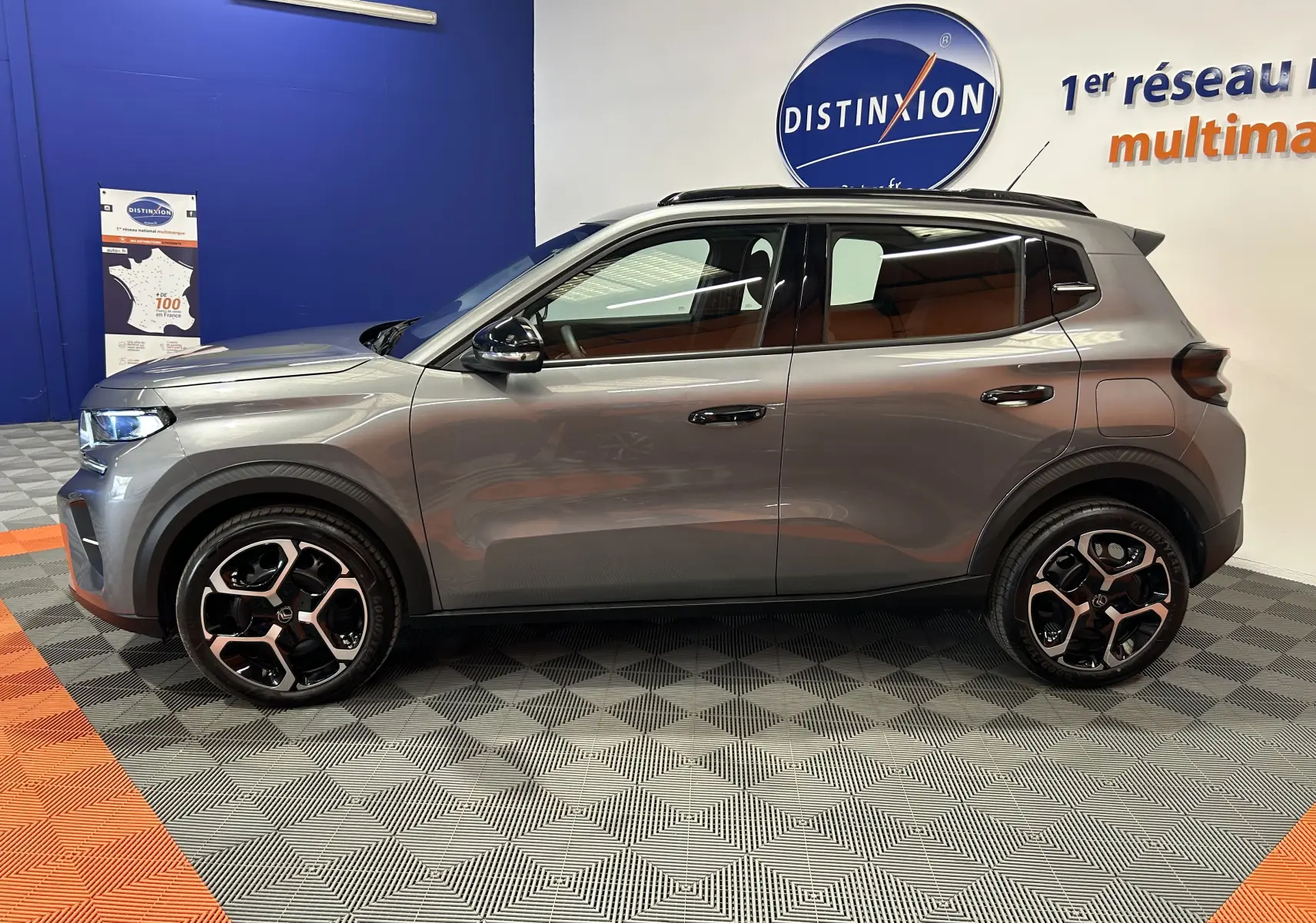 Vue de profil côté gauche d'une Citroën C3 2025 gris Artense avec jantes bi-ton et toit noir en showroom.