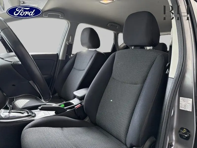 Vue intérieure côté conducteur de la Nissan Pulsar 2017 avec sièges tissu noirs et console centrale visible.