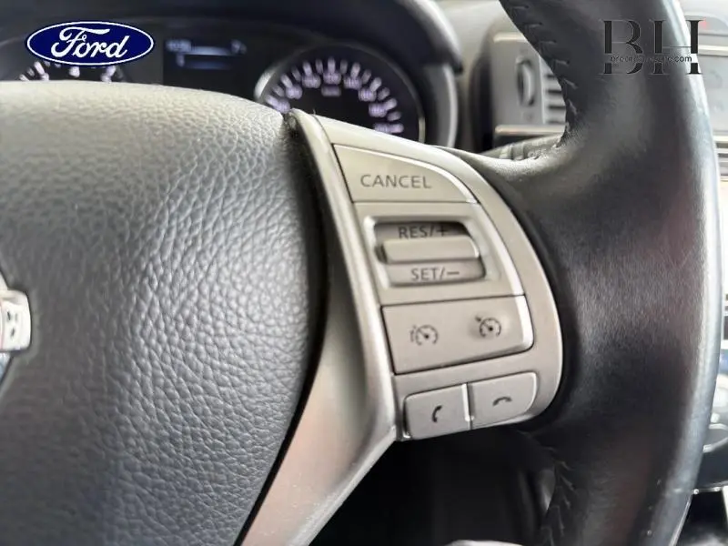 Gros plan sur le volant cuir noir de la Nissan Pulsar bronze ultime, avec commandes multifonctions côté droit visibles.