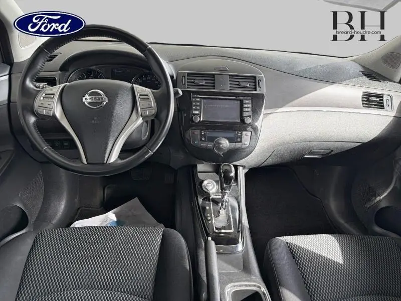 Vue intérieure avant centrée sur le tableau de bord et volant noir de la Nissan Pulsar 1.2 DIG-T 115ch avec console centrale et écran tactile.
