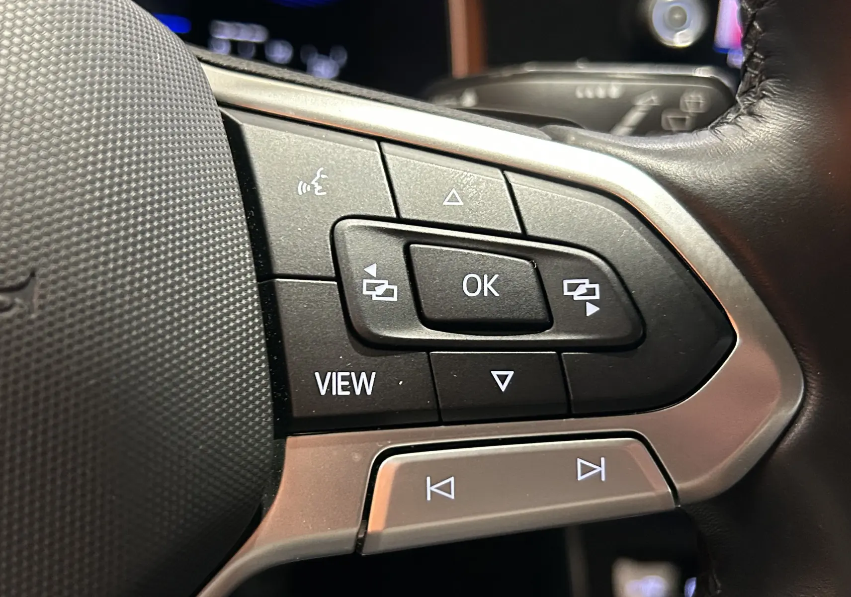 Gros plan sur les commandes multifonctions au volant en cuir noir du Volkswagen Taigo blanc Pur TSI 110 DSG7 Style 2022.