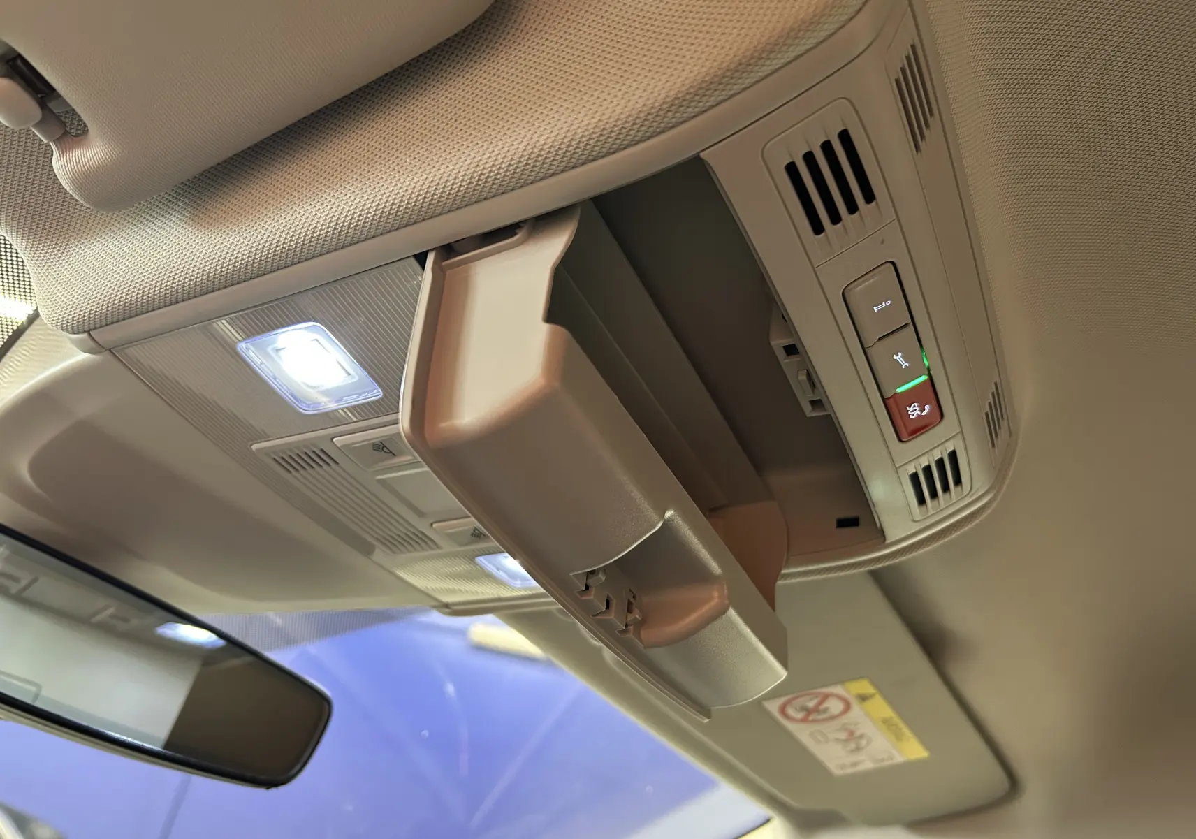 Rangement lunettes ouvert sur le plafond beige intérieur du Volkswagen Taigo TSI 110 DSG7 Style 2022, avec éclairage LED.