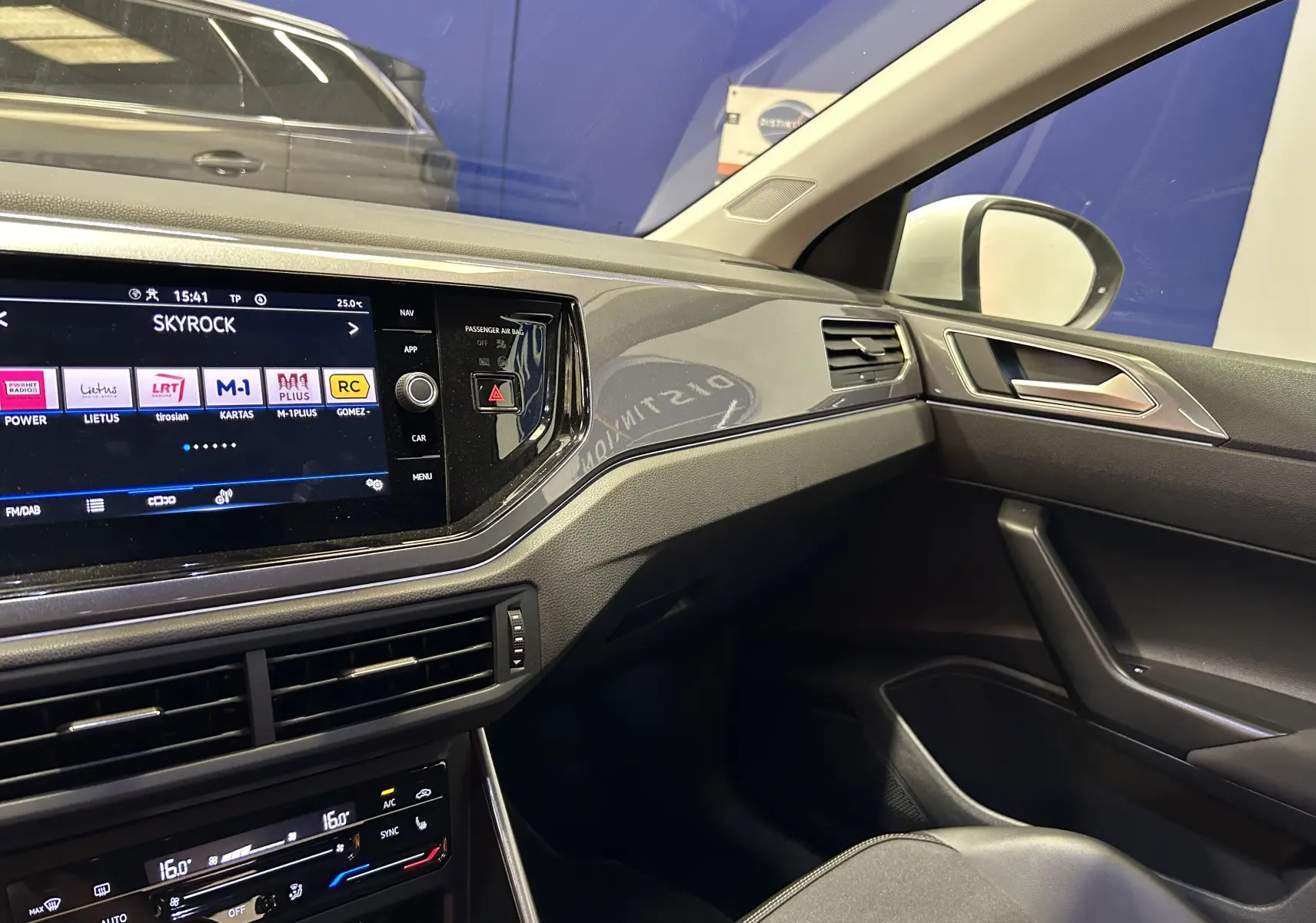 Intérieur côté passager du Volkswagen Taigo blanc, tableau de bord moderne avec écran tactile et commandes climatisation.