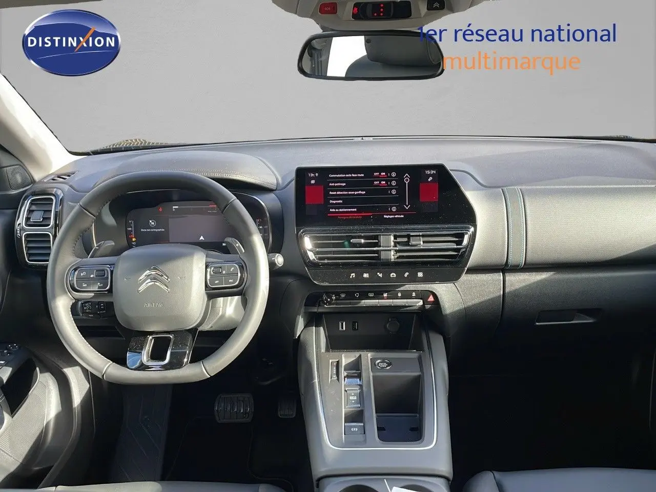 Vue intérieure frontale du tableau de bord et volant gris clair du Citroën C5 Aircross 2025 avec écran tactile central allumé.