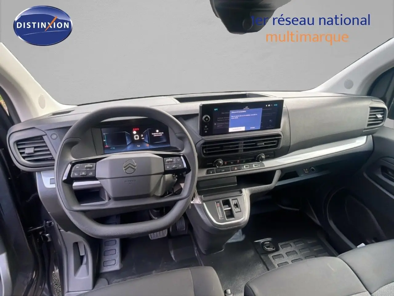 Vue intérieure du tableau de bord et volant du Citroën Jumpy gris titane, avec écran tactile central et commandes au volant.