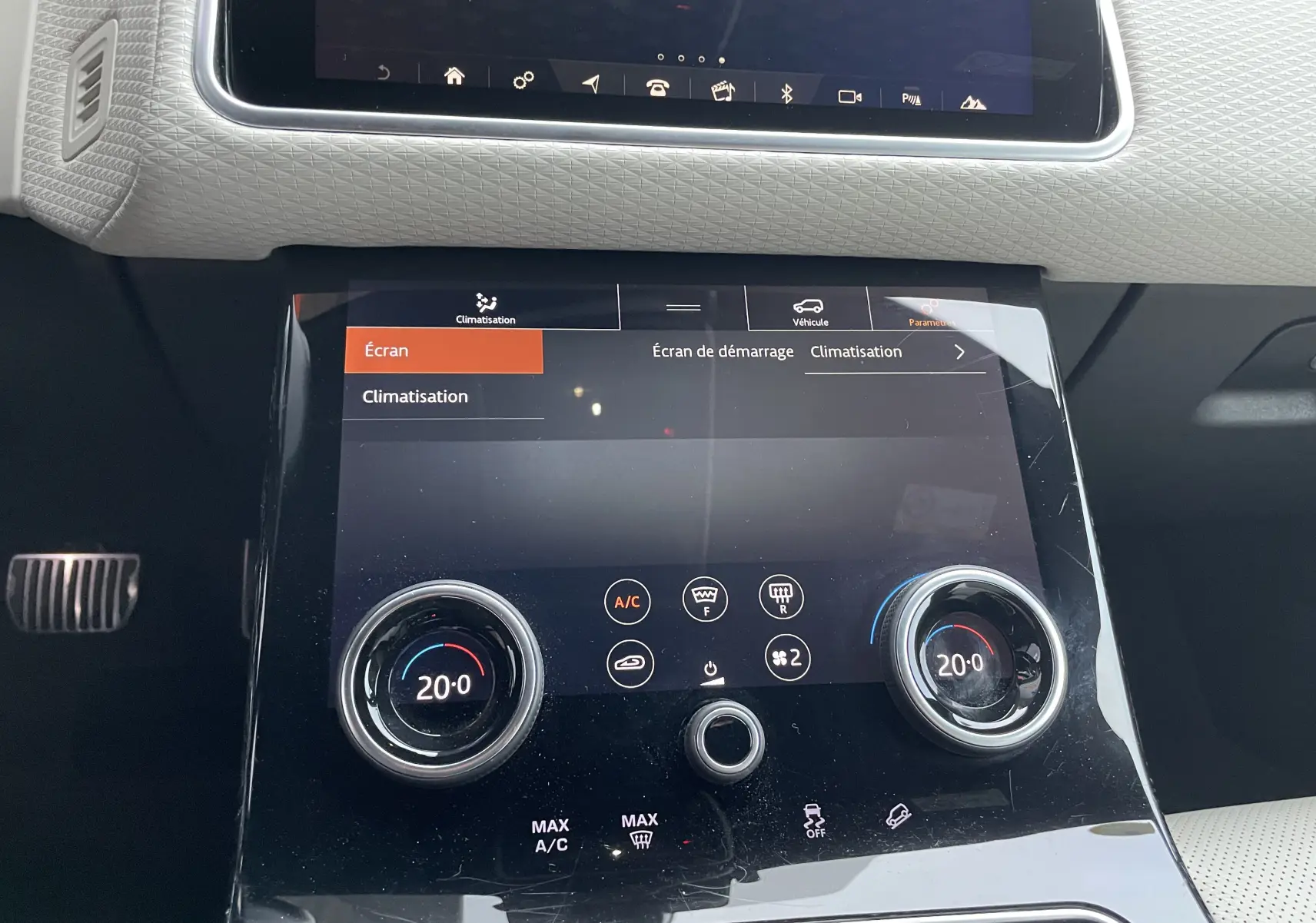 Gros plan sur la console centrale tactile du Range Rover Velar 2018, avec réglages climatisation à 20°C.