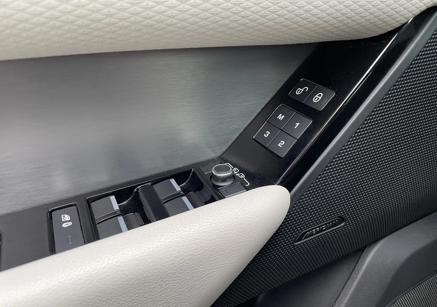 Détail de la porte côté conducteur du Range Rover Velar 2018 avec commandes de vitres, mémoire sièges et haut-parleur Meridian.