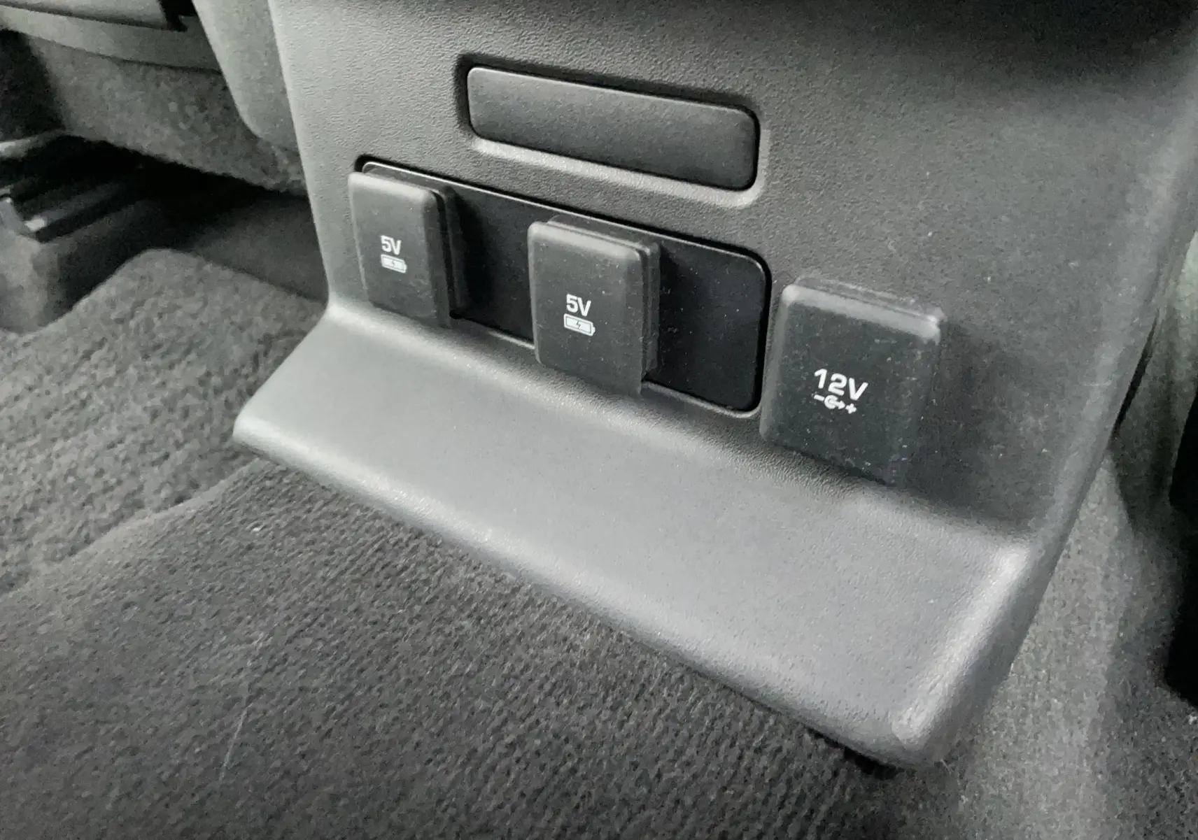 Prise 5V et 12V protégées au bas de la console centrale noire du Range Rover Velar D300 2018.