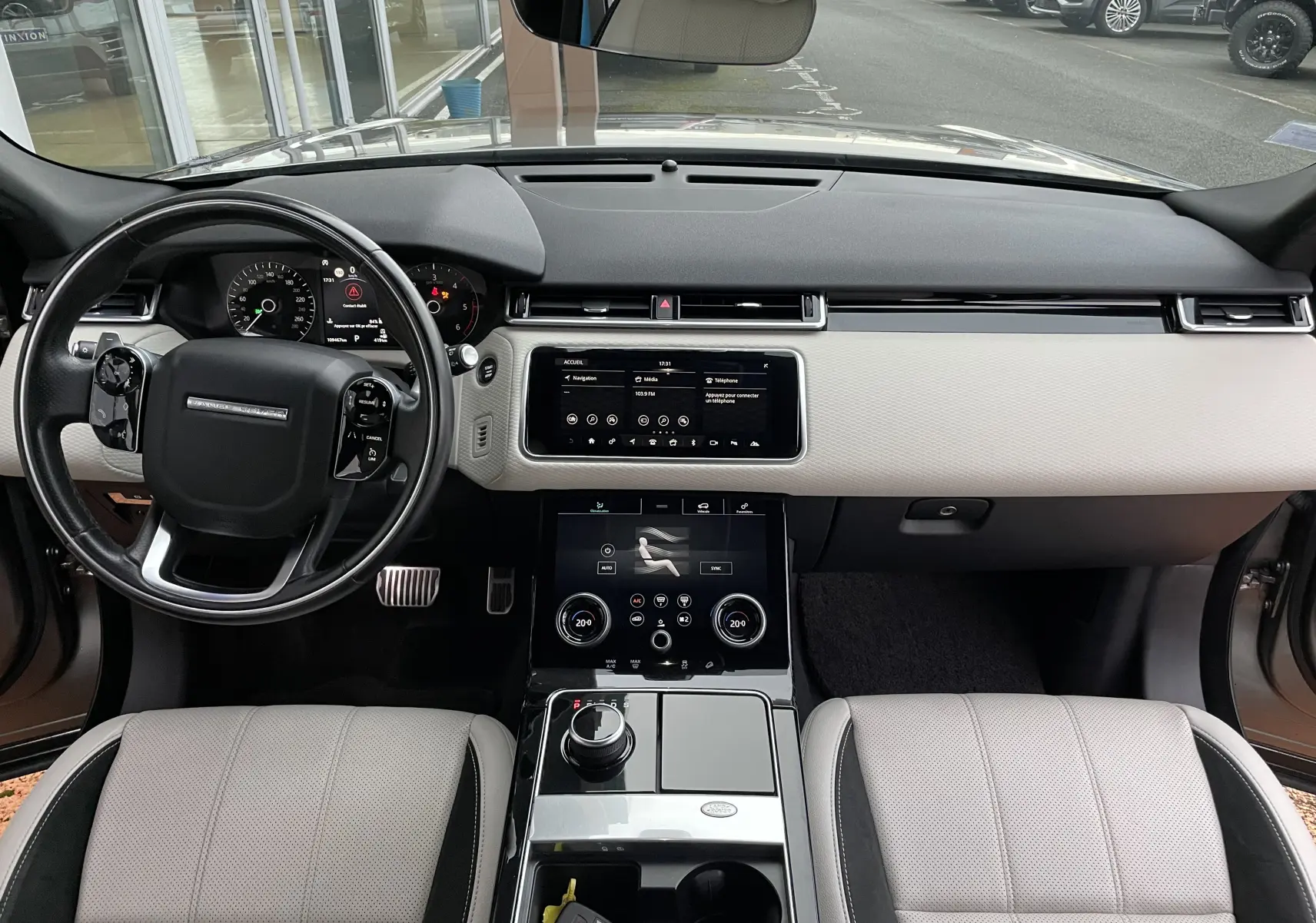 Intérieur du Range Rover Velar D300 2018 vu de face, tableau de bord noir et beige avec écran tactile central et volant cuir noir.