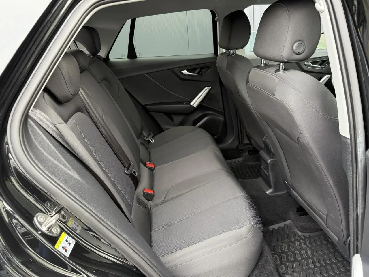Vue intérieure côté gauche des sièges arrière en tissu gris du SUV Audi Q2 noir Mythe 2023.