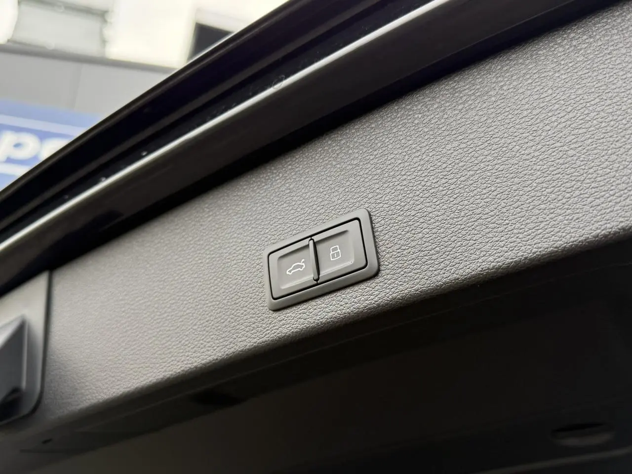 Boutons de commande du hayon électrique et de verrouillage sur le panneau intérieur du coffre d'un Audi Q2 noir Mythe.