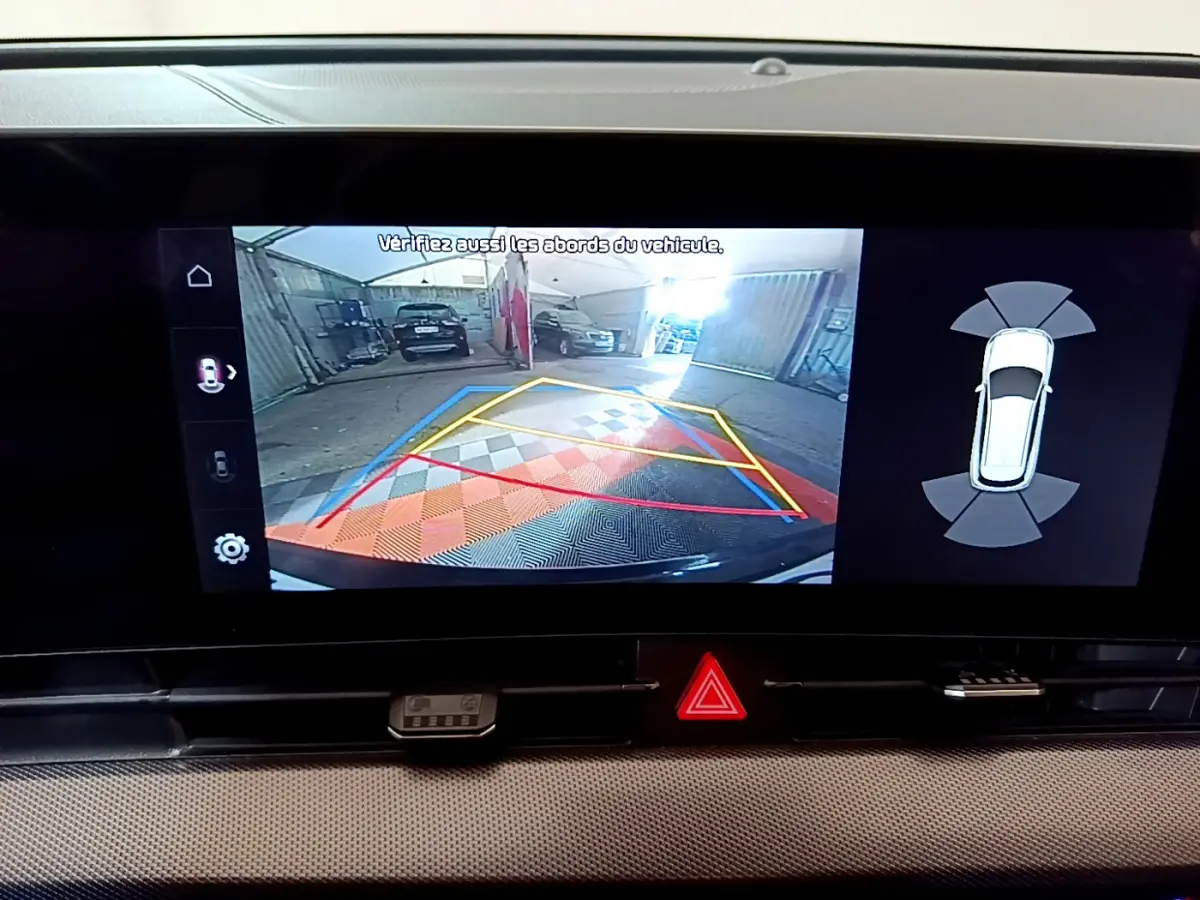 Écran tactile du Kia Sportage blanc montrant la caméra de recul avec guidage et capteurs de stationnement arrière.