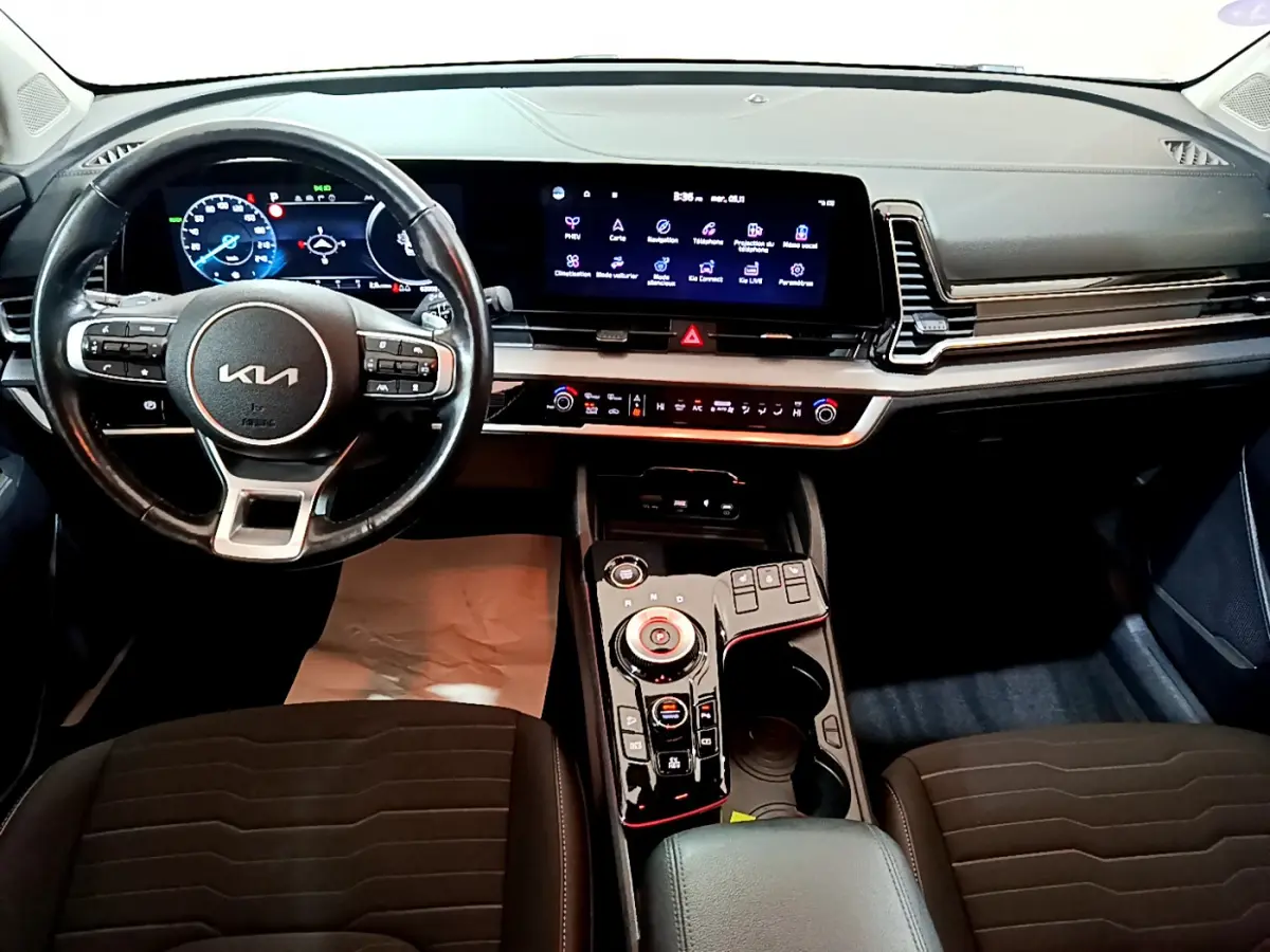 Vue intérieure du tableau de bord et volant cuir noir du Kia Sportage hybride rechargeable 2022 avec écran tactile large.