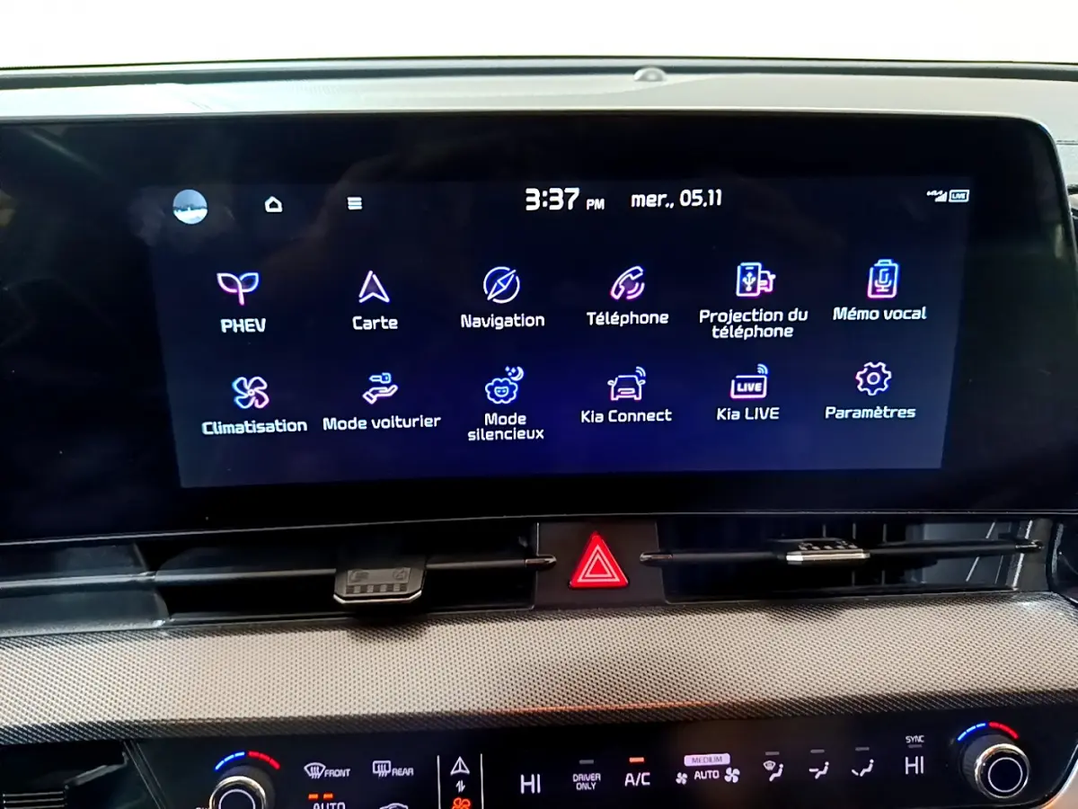 Écran tactile central affichant menu multimédia dans l'habitacle du Kia Sportage blanc, vue intérieure rapprochée.