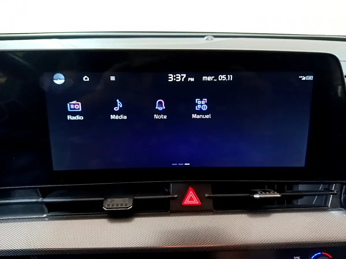 Écran tactile central du tableau de bord du Kia Sportage blanc 2022, affichant les menus Radio, Média, Note et Manuel.