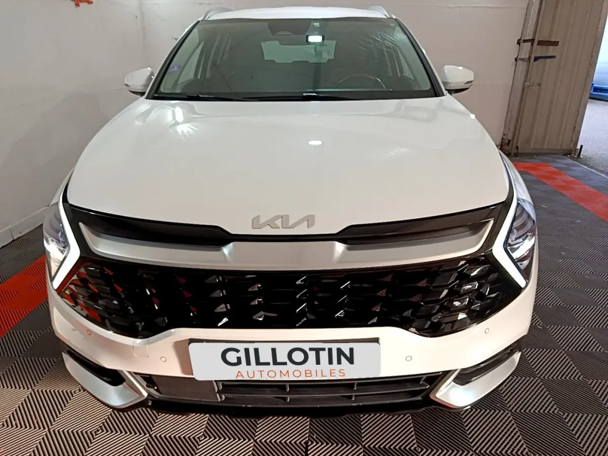 Vue frontale d'un KIA Sportage blanc 2022 avec calandre noire brillante et feux LED en forme de boomerang.