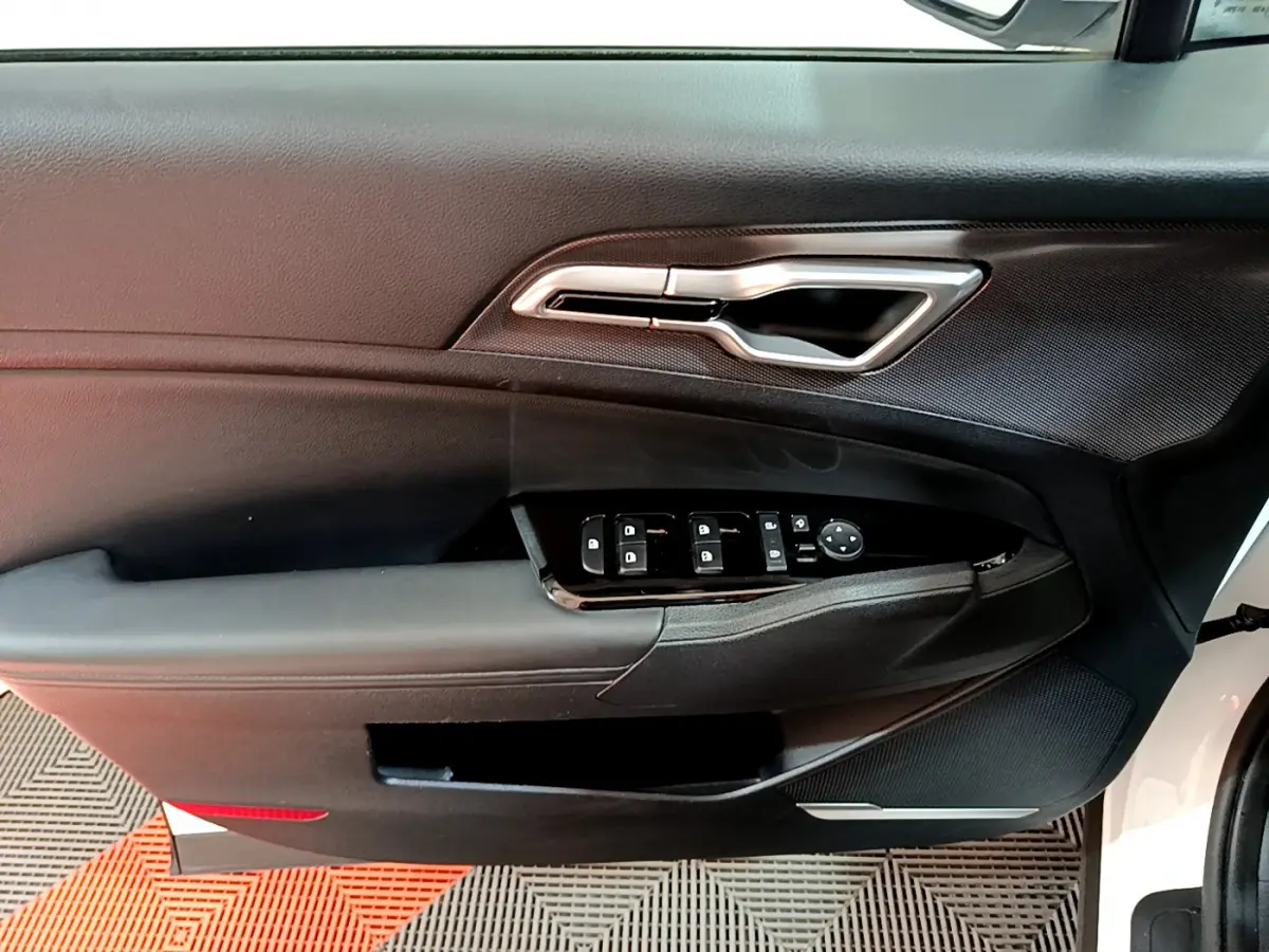 Intérieur côté conducteur de la porte d’un KIA SPORTAGE blanc 2022, avec commandes électriques et poignée argentée.