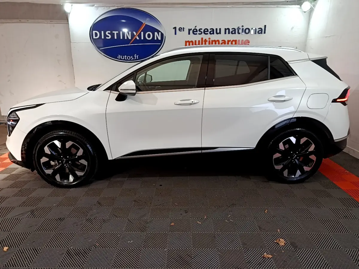 Profil côté gauche d'un KIA SPORTAGE blanc 2022 hybride rechargeable avec jantes noires et toit contrasté noir.