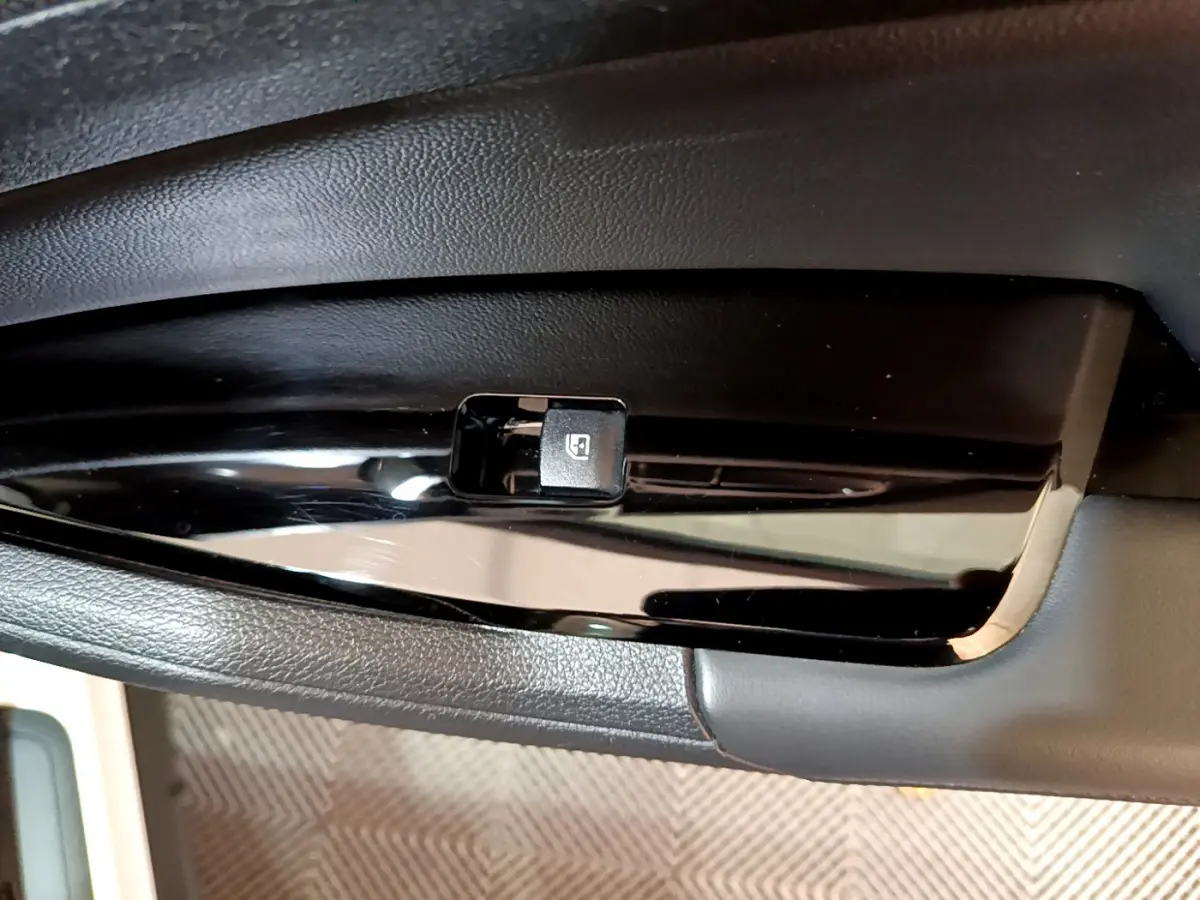 Gros plan sur le bouton de commande de lève-vitre électrique côté gauche dans l'habitacle du KIA SPORTAGE blanc 2022.