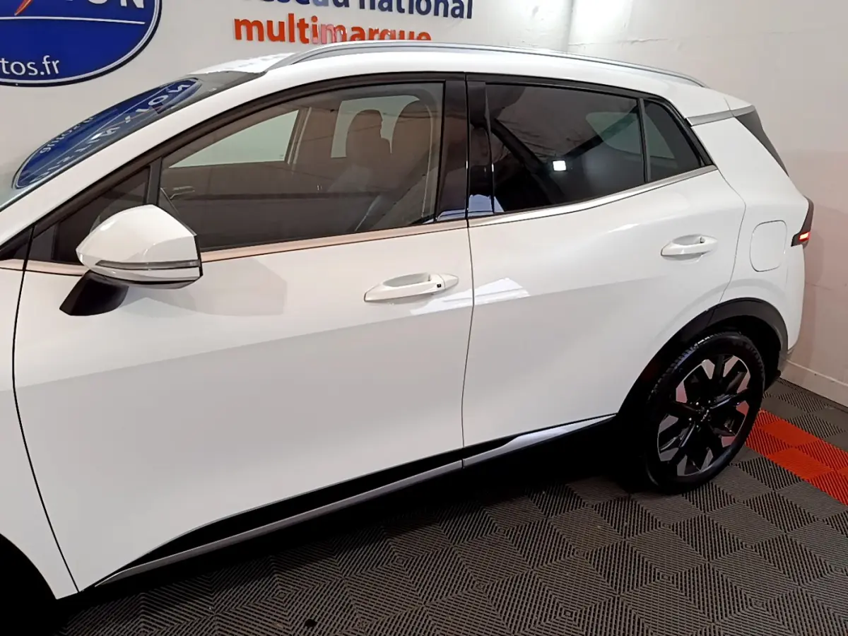 Vue latérale côté gauche du KIA SPORTAGE blanc 2022 avec jantes noires et rétroviseurs intégrant clignotants.