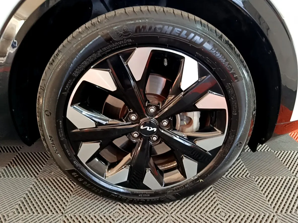 Gros plan sur la roue avant droite du KIA SPORTAGE blanc avec jante alliage noir et argentée au design moderne.