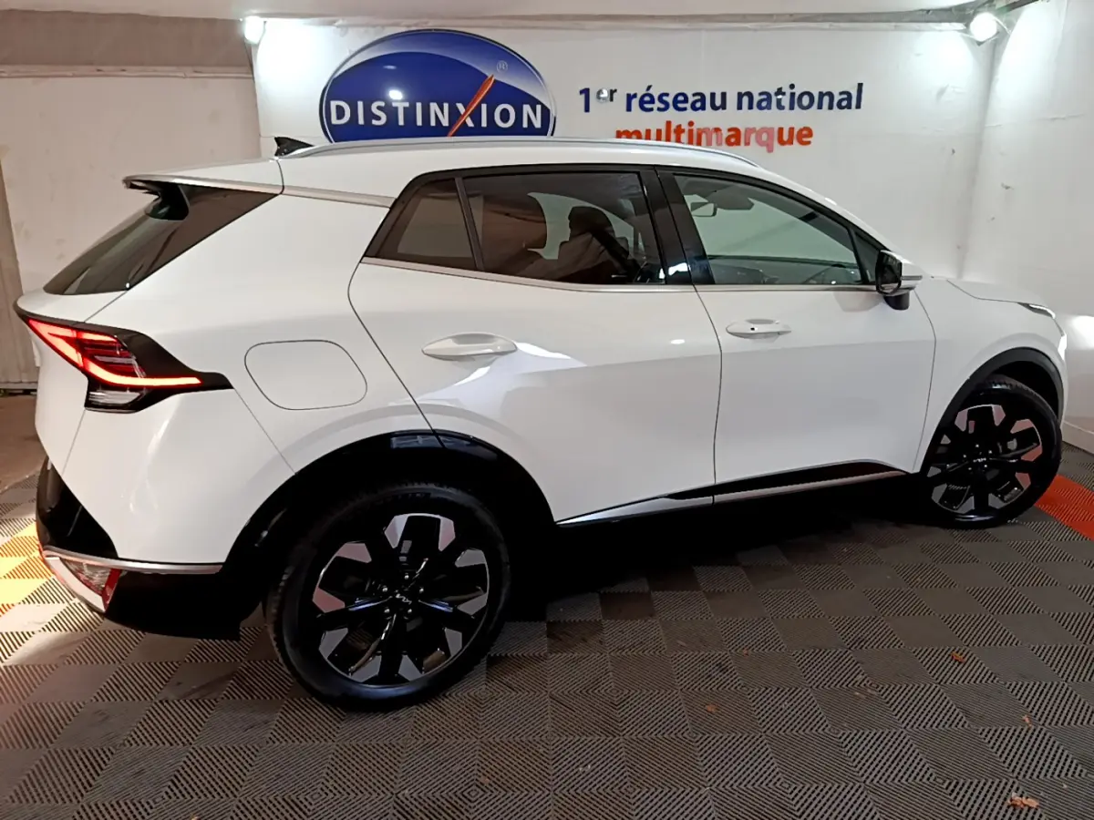Profil droit du KIA Sportage blanc 2022 hybride rechargeable avec jantes noires et feux arrière LED allumés.