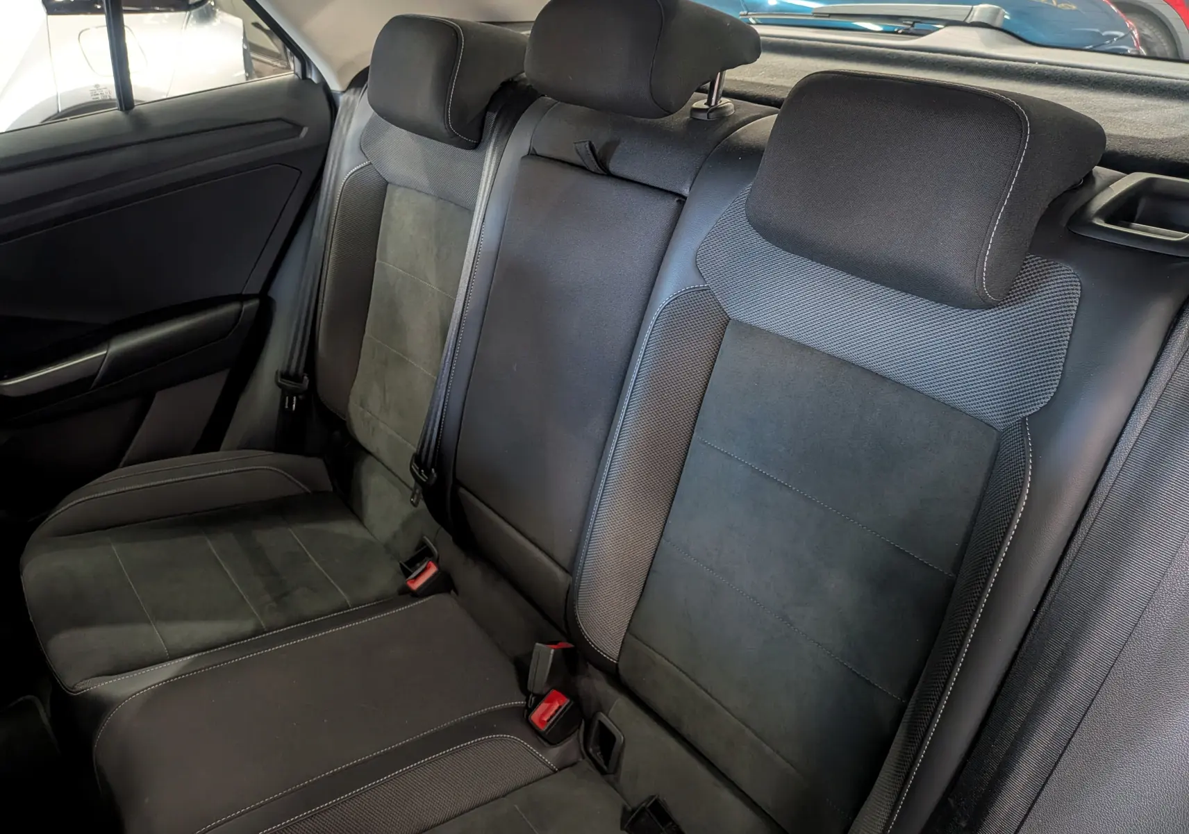 Vue intérieure des sièges arrière en tissu et cuir noir du Volkswagen T-Roc 1.5 TSI 2024, avec appuie-têtes réglables.