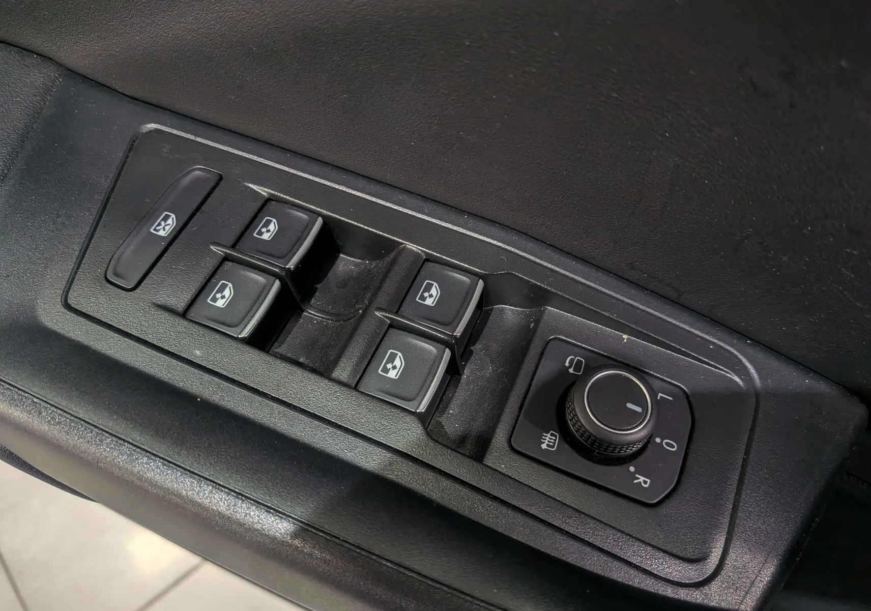 Commande des vitres et réglage des rétroviseurs sur la porte côté gauche d'un Volkswagen T-Roc gris Pyrite 2024.