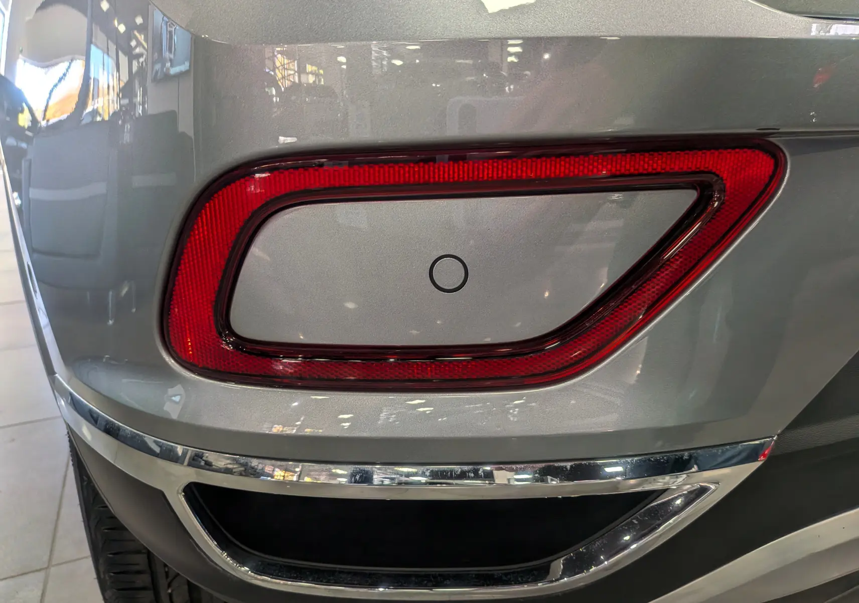 Gros plan sur le feu arrière droit rouge entouré de gris pyrite du Volkswagen T-Roc 2024, avec détail du pare-chocs chromé.