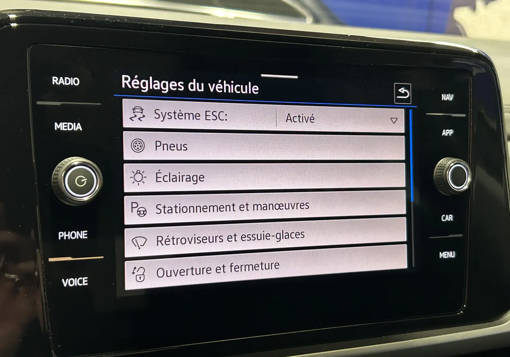Écran tactile central du Volkswagen T-Roc affichant les réglages du véhicule, interface moderne en intérieur noir.
