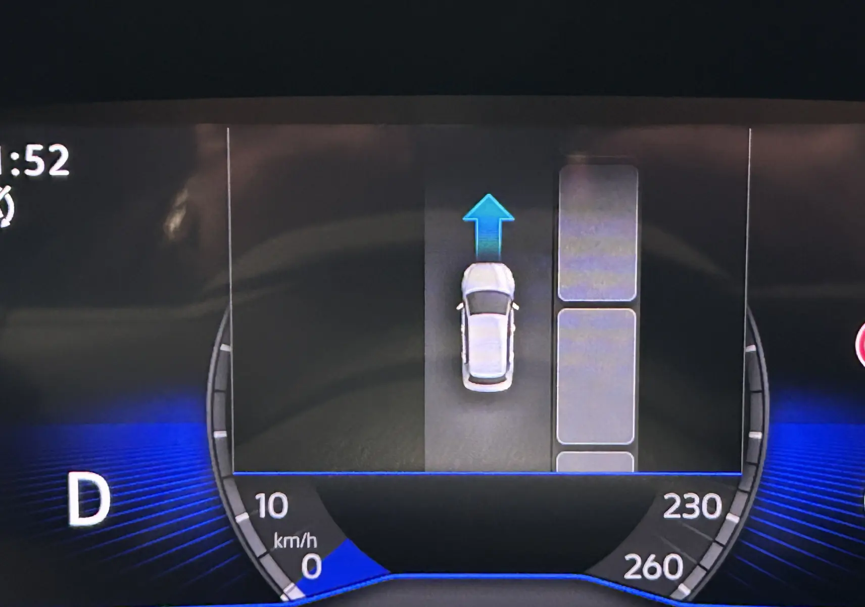 Affichage numérique du tableau de bord du Volkswagen T-Roc gris Indium, montrant la vitesse et l'assistance au stationnement en marche avant.