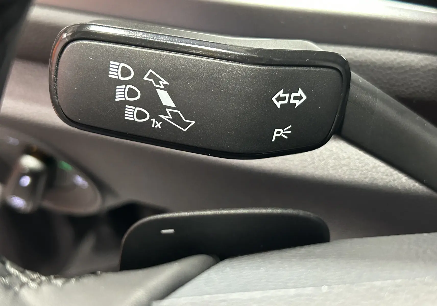 Gros plan sur la manette de clignotants et feux du Volkswagen T-Roc 2025, intérieur noir.