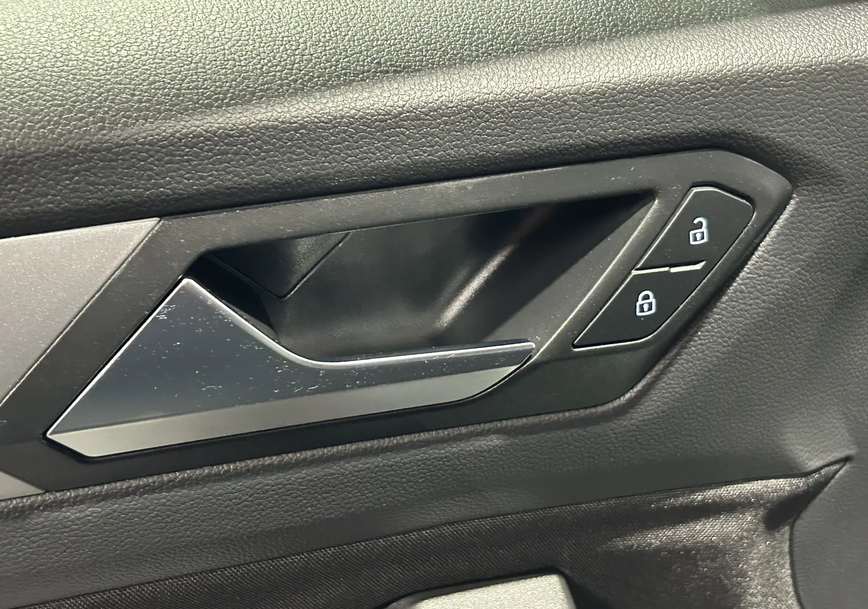 Poignée intérieure de porte côté conducteur du Volkswagen T-Roc 2025 avec boutons de verrouillage, finition noire.
