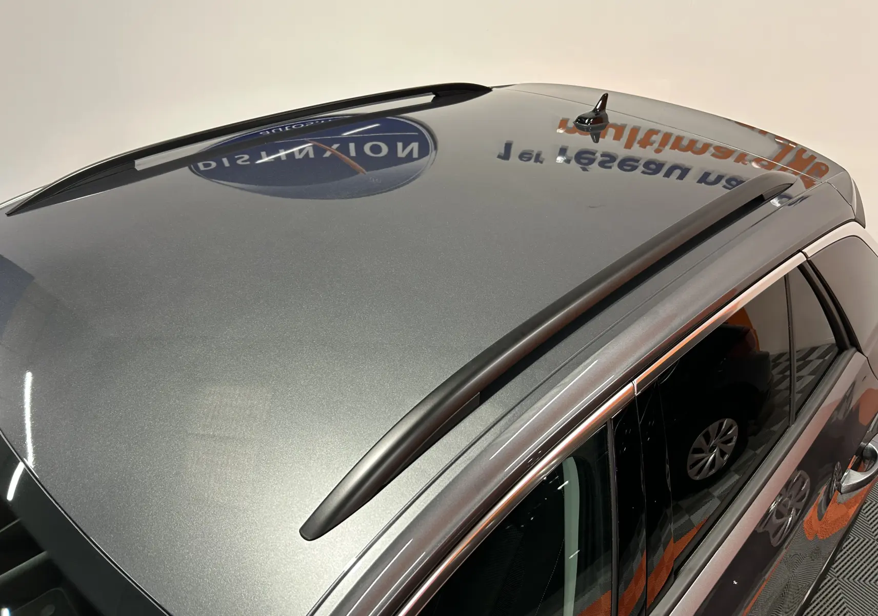 Vue en plongée du toit gris indium métallisé du Volkswagen T-Roc 2025 avec barres de toit noires et antenne requin.