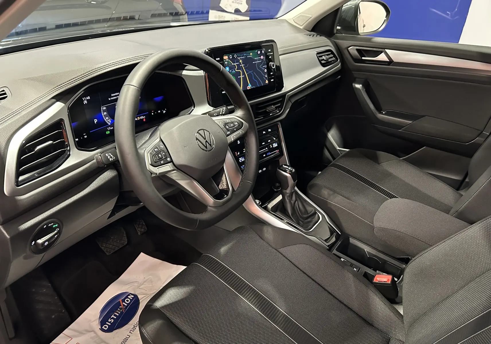 Vue intérieure côté conducteur du Volkswagen T-Roc 2025, avec tableau de bord numérique et sellerie tissu noire.