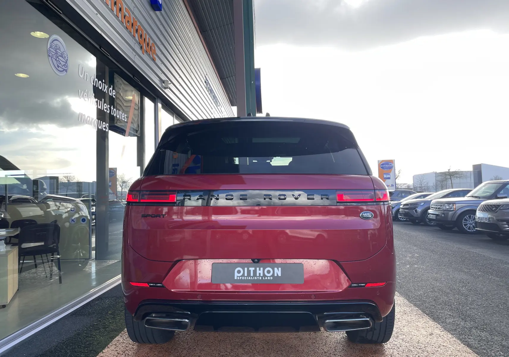 Vue arrière d'un Range Rover Sport P440 HSE R-Dynamic rouge Italian Racing, avec feux LED et double sortie d'échappement.