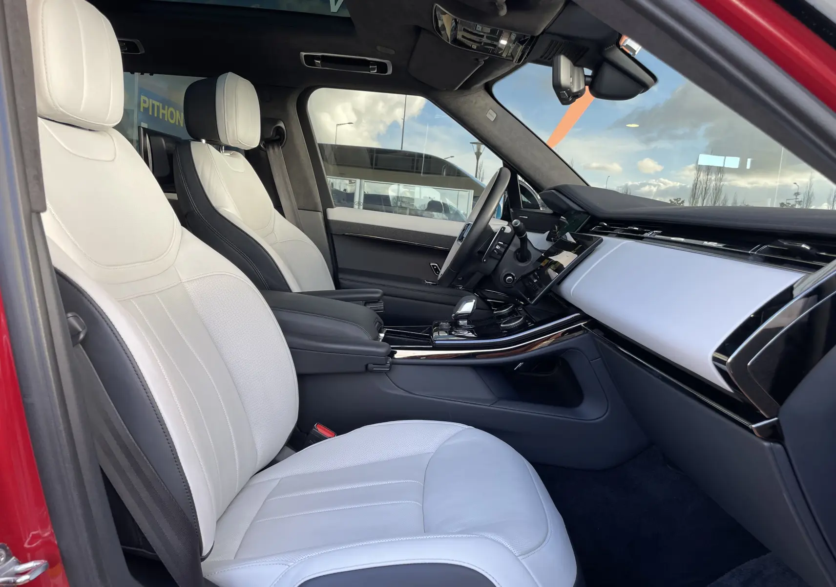 Vue intérieure côté gauche du Range Rover Sport P440 HSE R-Dynamic 2023, sièges cuir blanc et ciel de pavillon noir suédine.