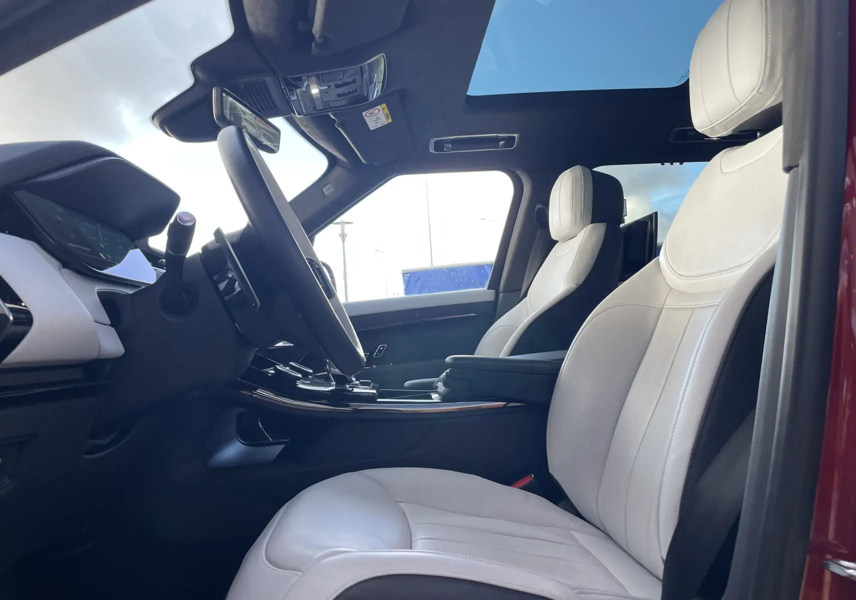 Vue intérieure côté conducteur du Range Rover Sport P440 HSE R-Dynamic 2023 avec sièges cuir blanc et toit ouvrant panoramique.