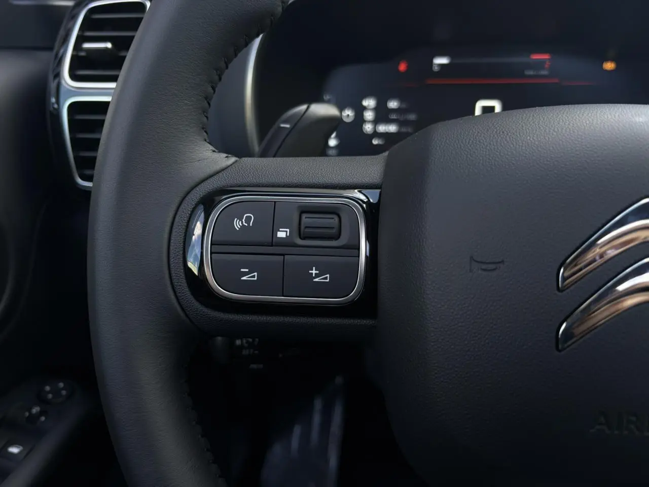 Gros plan sur le volant noir en cuir du Citroën C5 Aircross 2025, avec commandes intégrées à gauche.