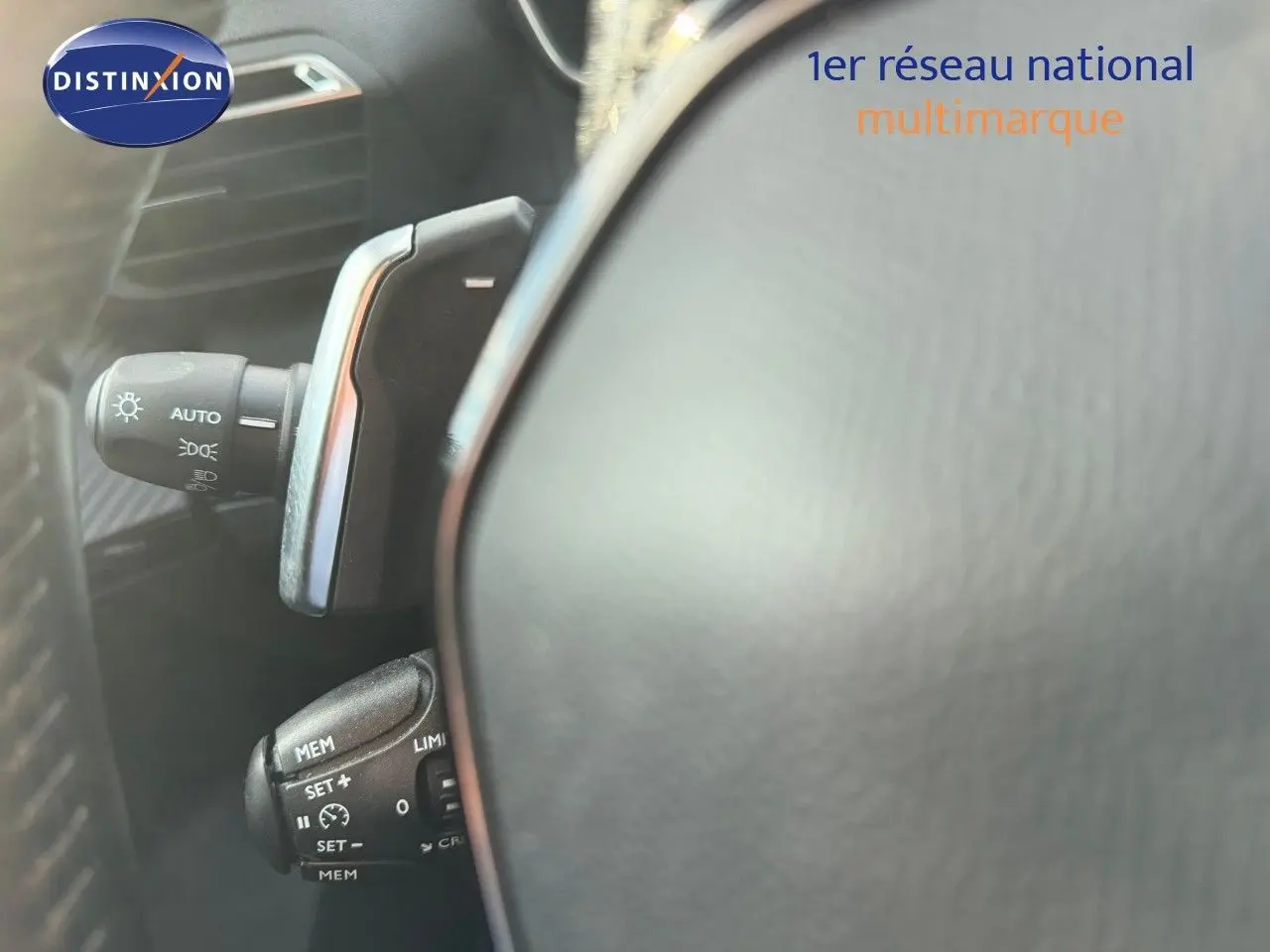 Détail du volant et des commandes de régulateur de vitesse d’un Peugeot 2008 gris Artense, intérieur noir.