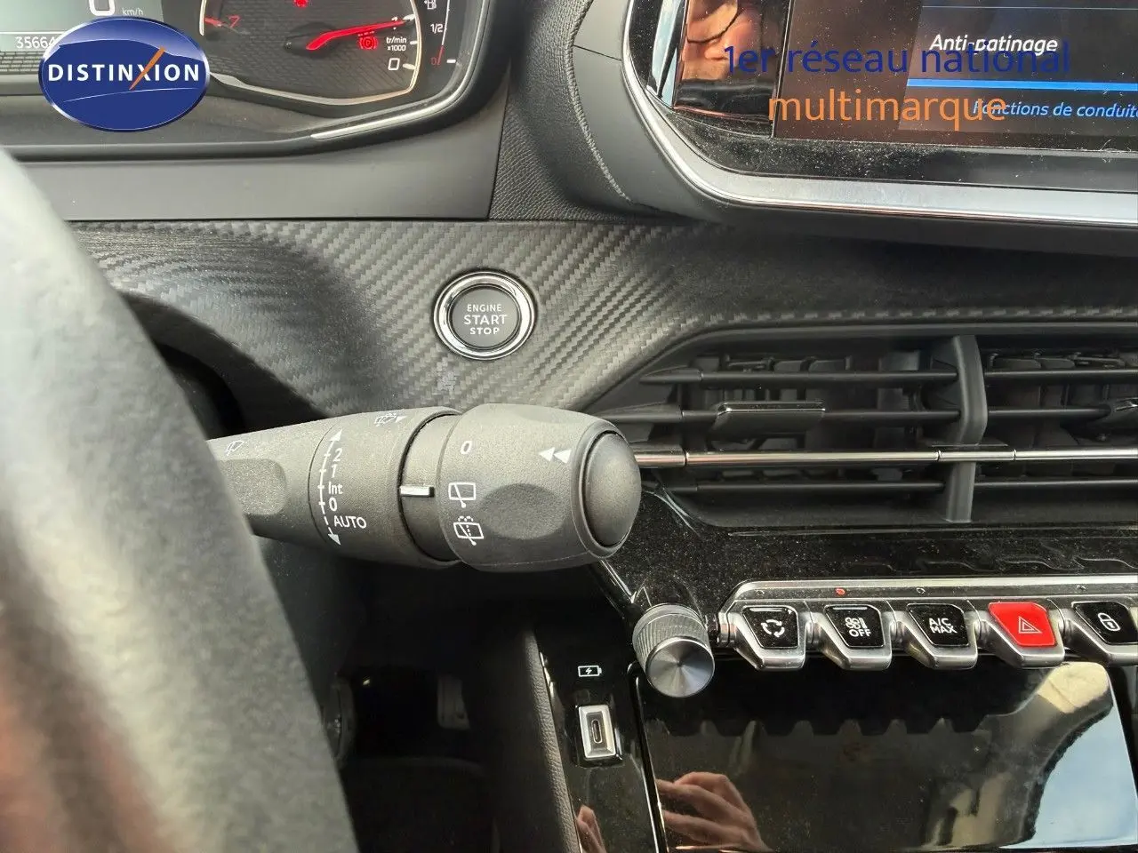 Vue intérieure du tableau de bord du Peugeot 2008 gris Artense, avec bouton start/stop et commandes de climatisation visibles.