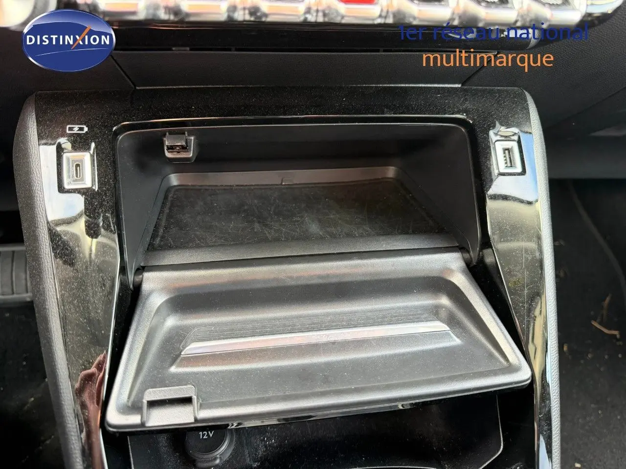 Gros plan sur la console centrale du Peugeot 2008 gris Artense, montrant un compartiment de rangement ouvert avec ports USB.