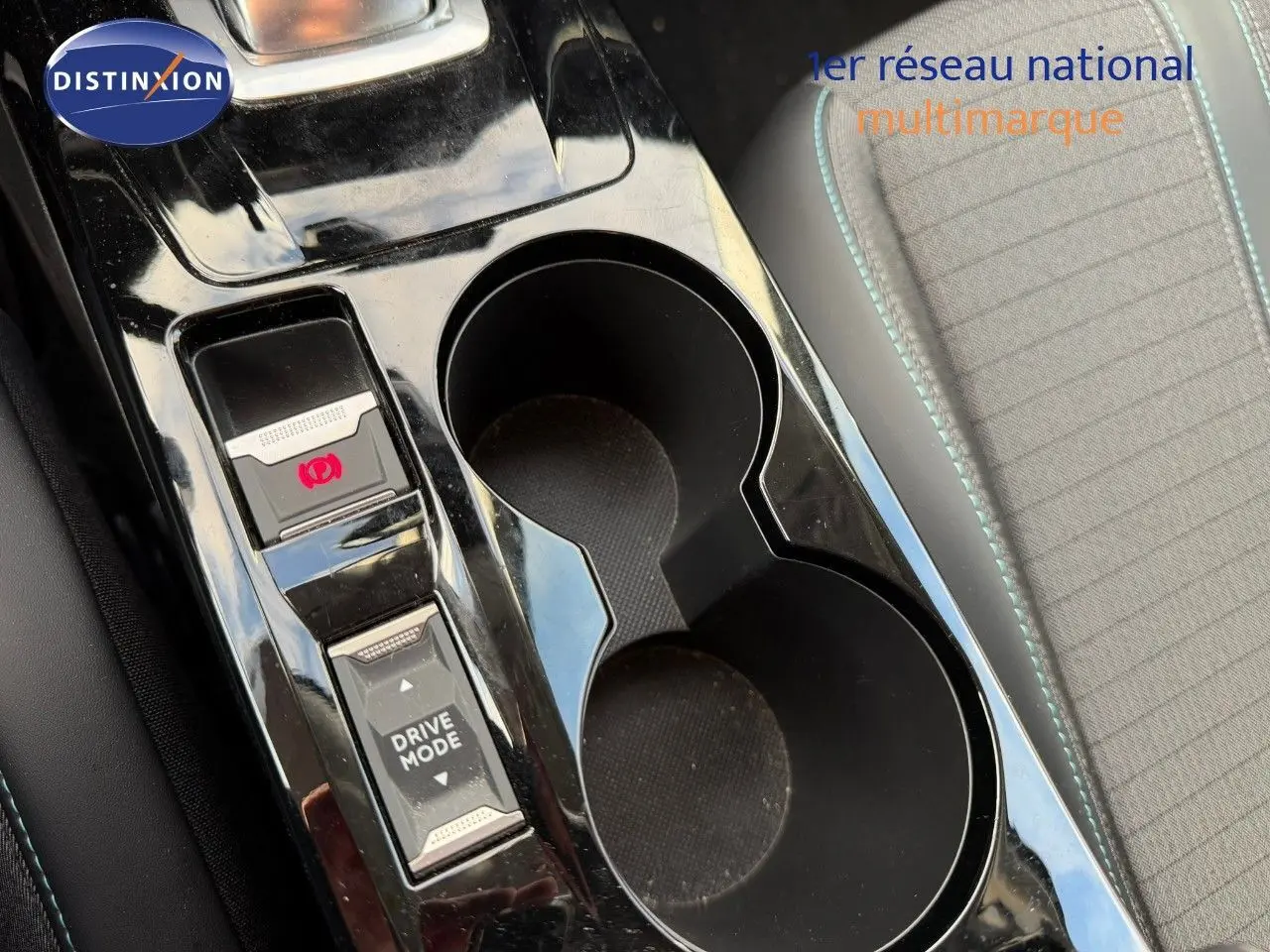 Gros plan sur la console centrale noire brillante du Peugeot 2008 1.2 PureTech, avec boutons frein à main et mode de conduite.