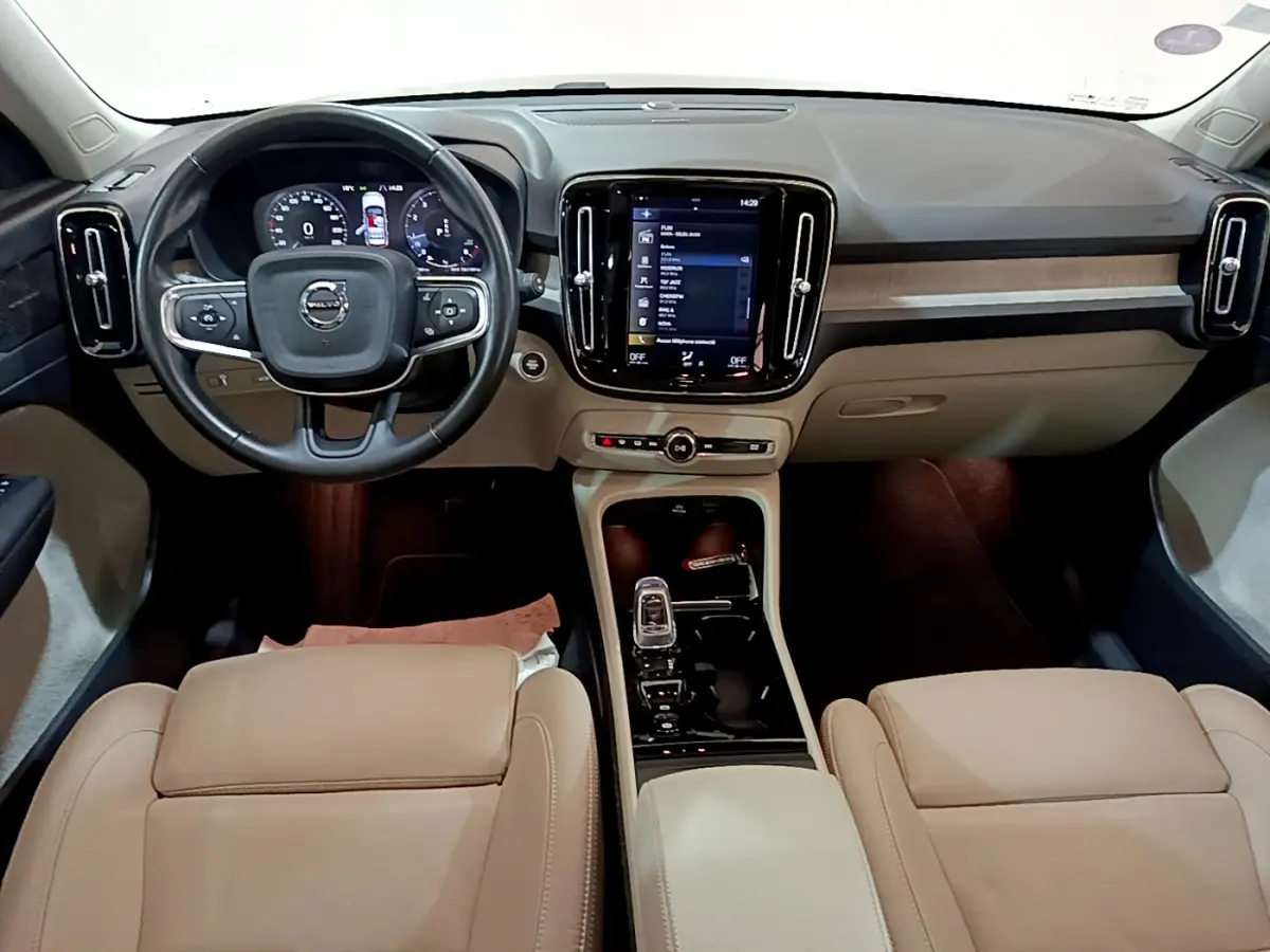 Intérieur du Volvo XC40 T3 2020 vu de face, tableau de bord beige avec écran tactile central et volant cuir noir.